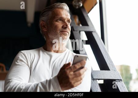 Business-Lifestyle. Casual Grey-haired Reife professionelle gut aussehende Geschäftsmann in der Nähe von Fenster in seinem Büro Stockfoto