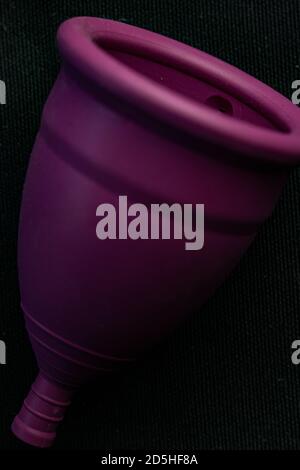 Nahaufnahme einer violetten Menstruationstasse auf schwarzem Hintergrund Stockfoto