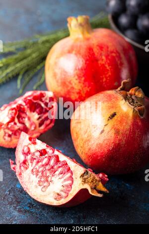 Frische Granatäpfel in Scheiben. Ganze Früchte und Scheiben von reifem Granatapfel liegen auf einem Tisch. Stockfoto