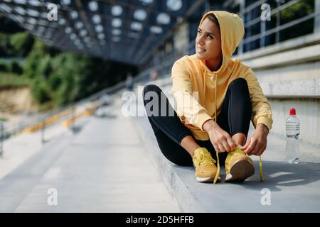 Eine athletische Frau, die vor dem Laufen Schnürsenkel an Turnschuhen bindet Stockfoto