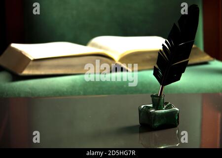 Federstift mit Tintenfass und altem Buch. Vintage-Hintergrund. Stockfoto