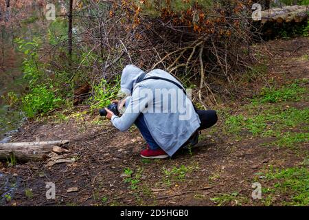 Ein junger Mann dreht ein Video mit einer Spiegelreflexkamera in der Natur im Wald am See. Stockfoto