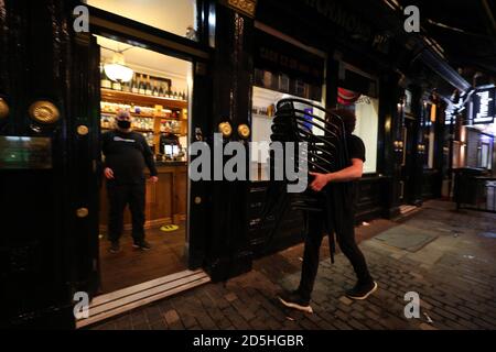 Die Mitarbeiter des Richmond Pub in Liverpool bringen Tische und Stühle ein, in der Nacht bevor neue Maßnahmen in der Region in Kraft treten, nachdem die sechs Bezirke in der Liverpool City Region auf Rang 3, dem höchsten Niveau, Des neuen Coronavirus-Warnsystems der Regierung. Stockfoto