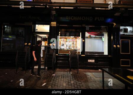 Die Mitarbeiter des Richmond Pub in Liverpool bringen Tische und Stühle ein, in der Nacht bevor neue Maßnahmen in der Region in Kraft treten, nachdem die sechs Bezirke in der Liverpool City Region auf Rang 3, dem höchsten Niveau, Des neuen Coronavirus-Warnsystems der Regierung. Stockfoto