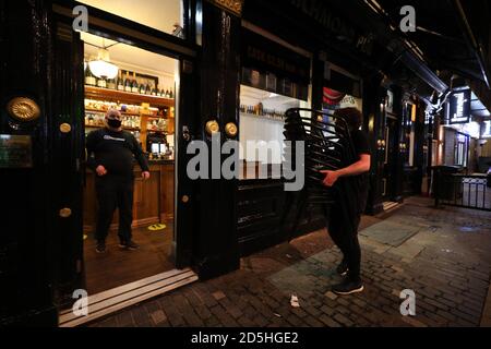 Die Mitarbeiter des Richmond Pub in Liverpool bringen Tische und Stühle ein, in der Nacht bevor neue Maßnahmen in der Region in Kraft treten, nachdem die sechs Bezirke in der Liverpool City Region auf Rang 3, dem höchsten Niveau, Des neuen Coronavirus-Warnsystems der Regierung. Stockfoto