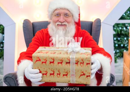 Portrait echten authentischen Weihnachtsmann mit Weihnachtsgeschenken in den Händen sitzen in der Shopping Mall. Stockfoto