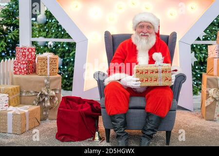 Portrait echten authentischen Weihnachtsmann mit Weihnachtsgeschenken in den Händen sitzen in der Shopping Mall. Stockfoto