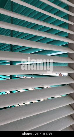 Fensterläden aus Holz in weiß und blau lackiert. Fensterläden im Retro-Stil. Struktur mit Streifenmuster Stockfoto