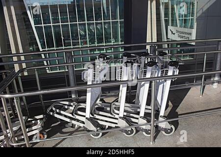 Gepäckwagen in einem Flughafen und ein Schild Abfahrt am Ein Hintergrund (Открытие is Departure auf russisch) Stockfoto