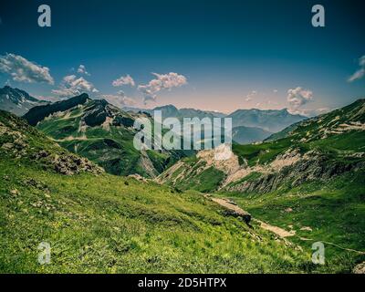 Berggrasstrecken mit felsigen Hügeln und Schnee. Trekking im Sommer Stockfoto