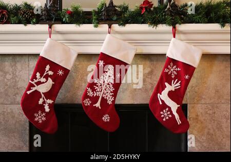 Drei rote weihnachtsstrümpfe auf Kaminmantel Stockfoto