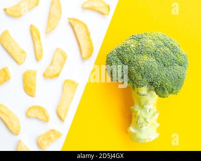 Gesunde vs ungesunde Lebensmittel und Diät-Konzept. Grüner Brokkoli auf gelb und pommes Frites Kartoffeln isoliert auf weißem Farb-Studio-Hintergrund mit Kopie Stockfoto