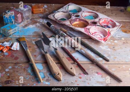 Künstler Schreibtisch und Materialien mockup.Various Bürsten, Pallete Messer und Pallete.The Holzschreibtisch ist mit schönen verschiedenen Farben bedeckt. Stockfoto