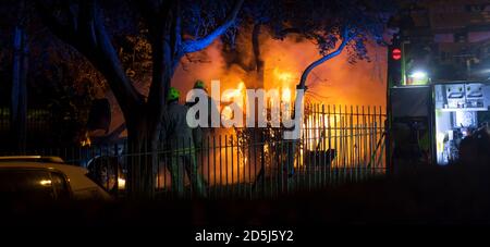 Feuerwehrleute, die nachts einen Brand in Großbritannien bekämpfen.Sie löschen ein Auto in Brand mit Hilfe von Spezialausrüstung. Stockfoto