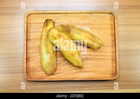 Drei gebratene Bananen werden auf ein Holztablett gestellt, auf dem Foto von oben. Stockfoto