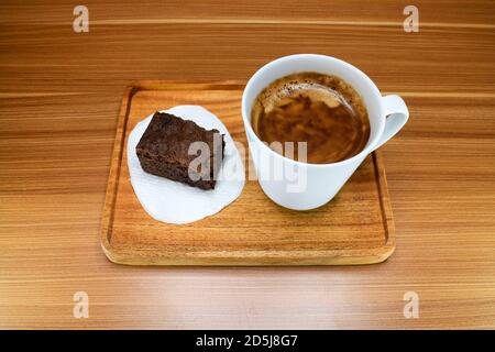 Eine Tasse Kaffee mit Schokolade Brownie Kuchen serviert auf einem Holztablett Stockfoto