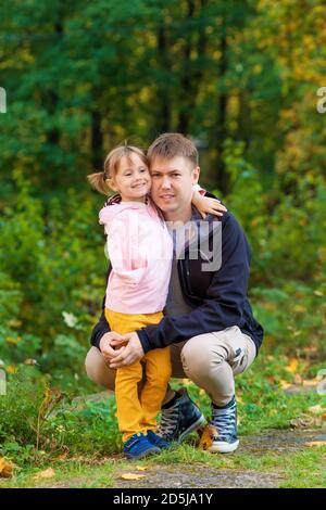 Ein Mädchen mit einem gebrochenen Arm umarmt ihren Vater Ein alter Park auf einem Herbstspaziergang Stockfoto