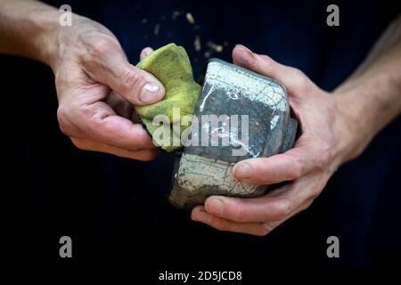 Waddewitz, Deutschland. Oktober 2019. Eine fertig gefeuerte Raku-Schale wird von Ruß und Asche befreit. Einmal im Jahr feuert Keramiker Mathias Stein Teeschalen mit einer gesprungenen Glasur - ein Craquelé - in einem selbstgebauten Holzofen an. Die feinen Risse werden durch den Temperaturabfall verursacht, wenn die glühenden Schüsseln mit langen Zangen aus dem Ofen gezogen werden. Die spezielle Brenntechnik stammt aus Japan und wird Raku genannt. Quelle: Sina Schuldt/dpa/Alamy Live News Stockfoto