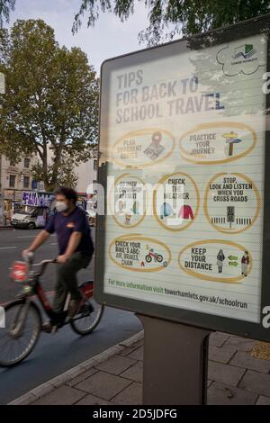 Anwohner Radfahren in Whitechapel, mit Schildern beraten, um sichere soziale Distanz wegen Coronavirus / Covid-19 Pandemie in London, England, Großbritannien zu halten Stockfoto