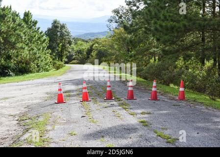 Straßenkegel / orangefarbene Verkehrskegel stehen in einer Reihe Auf Asphalt auf der Straße Berg Stockfoto