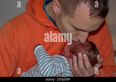 Portrait des Mannes hält und küsst neugeborenes Baby Stockfoto