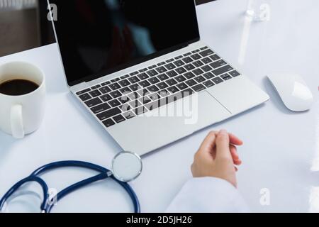 Mediziner arbeitet am Schreibtisch. Nahaufnahme des Stethoskops. Hand der asiatischen Frau Arzt erklären, um Patienten auf dem Tisch vor Laptop-Computer an der hos Stockfoto