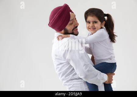 EINE SIKH-TOCHTER IN DEN ARMEN DES VATERS VERBRINGT ZEIT ZUSAMMEN Stockfoto