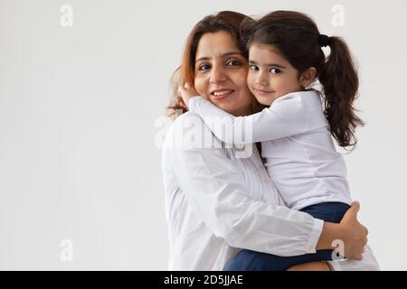 EINE TOCHTER UMARMTE IHRE MUTTER UND SCHAUTE AUF DIE KAMERA Stockfoto