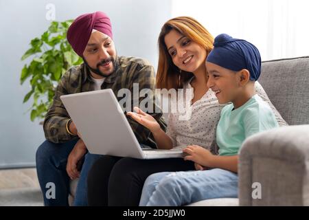 EIN SIKH-SOHN LERNT BEGEISTERT VON VATER UND MUTTER EIN NOTEBOOK Stockfoto