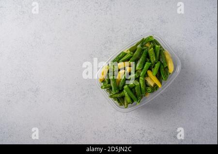 Gefrorenes Gemüse grüne Hülsen Bohnen in Kunststoff-Tablett auf grauem Hintergrund, Konzept Diäten und gesunde Ernährung mit Kopierer Platz Stockfoto