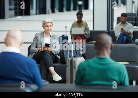 Gruppe von Leuten, die im Warteraum sitzen und darauf warten Ihr Flug am Flughafen Stockfoto