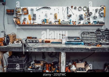 Moto Workshop mit Handwerkzeugen. Werkbank mit Schlüsseln, Schraubendrehern, Ploskobellen, Isolierband, Klebeband an der Wand. Tisch mit Motorrad pa Stockfoto