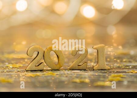 2021 Holznummern auf Bokeh-Hintergrund in goldenen Farben. Festliche Grußkarte für Neujahr mit Kopieplatz Stockfoto