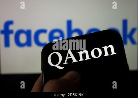 QAnon im Vergleich ZU FACEBOOK. QAnon-Unternehmenslogo auf dem Smartphone, das auf Facebook-Logos platziert ist. Konzept für das Verbot von QAnon in sozialen Medien. Stockfoto