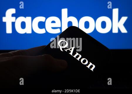 QAnon im Vergleich ZU FACEBOOK. QAnon-Unternehmenslogo auf dem Smartphone, das auf Facebook-Logos platziert ist. Konzept für das Verbot von QAnon in sozialen Medien. Stockfoto