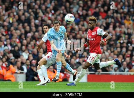 James Milner (Mitte) von Manchester City kämpft um den Ball Arsenals Alex Song (rechts) und Mikel Arteta (links) Stockfoto