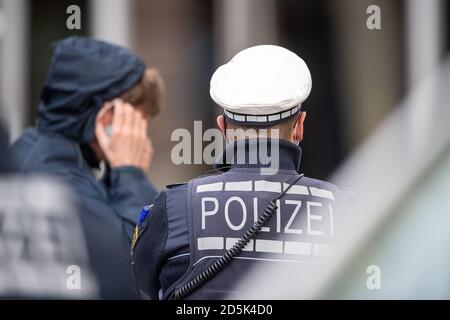 Stuttgart, Deutschland. Oktober 2020. Ein Polizist steht im Stadtzentrum vor einem jungen Mann, der sich den Mund und die Nase aufsetzt, nachdem ihm der Polizist gesagt hat, dies zu tun. In der Landeshauptstadt treten strengere Coronaregeln in Kraft. Unter anderem besteht die Verpflichtung, einen Mund- und Nasenschutz innerhalb des City Rings zu tragen. Quelle: Sebastian Gollnow/dpa/Alamy Live News Stockfoto