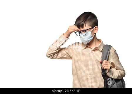 Kaukasischen weißen Schuljunge trägt eine Schutzmaske berühren einen Kranken Kopf auf einem weißen isolierten Hintergrund Stockfoto