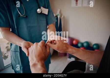 Nahaufnahme einer jungen Krankenschwester, die männliche Patienten in die Hände hält Krankenhaus Stockfoto