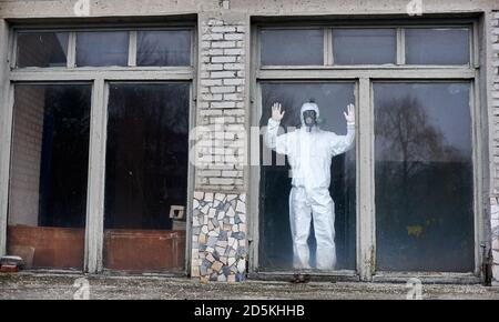 Horizontale Momentaufnahme eines Wissenschaftlers, der in einem der großen Fenster mit Stoppschild steht, das andere Fenster ist gebrochen, Konzept von verlassenen Orten Stockfoto