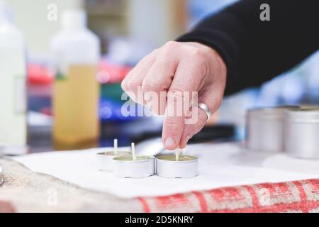 Ein Chandler oder Kerzenmacher fügt einen Docht zu duftenden Handgemachte Kerzen Stockfoto