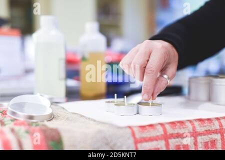 Ein Chandler oder Kerzenmacher fügt einen Docht zu duftenden Handgemachte Kerzen Stockfoto