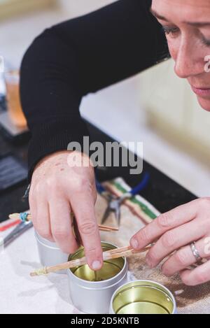 Ein Chandler oder Kerzenmacher fügt einen Docht zu duftenden Handgemachte Kerzen Stockfoto