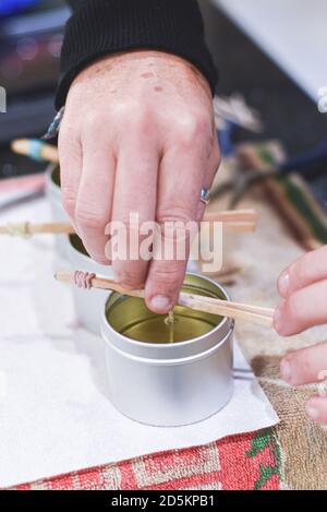 Ein Chandler oder Kerzenmacher fügt einen Docht zu duftenden Handgemachte Kerzen Stockfoto