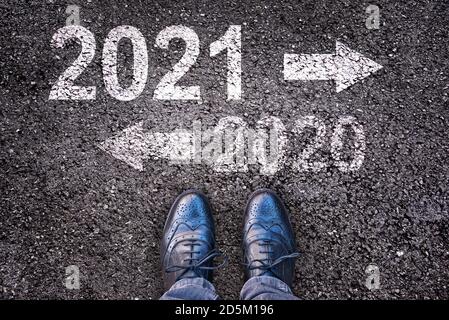 2021 und 2020 mit Richtungspfeilen auf Asphalt Straßenhintergrund mit Beinen Stockfoto