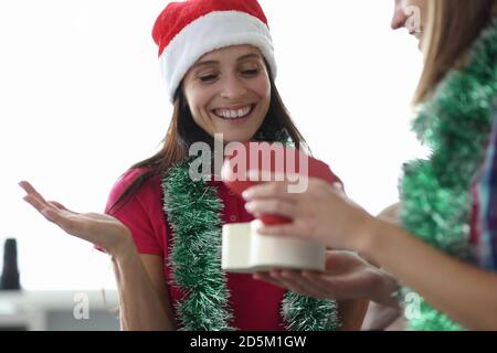 Lächelnde Frau in weihnachtsmann Hut schaut auf Geschenkbox Stockfoto