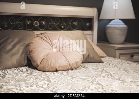 Fragment der Schlafzimmer im klassischen Stil. Das Kopfteil ist mit Blumenmustern und Samtkissen ausgestattet. Sanfte Abendbeleuchtung Stockfoto