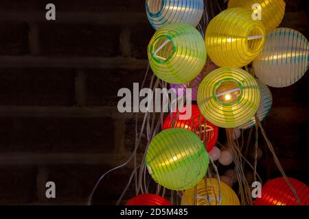 Bunte Papier Laterne Märchen Lichter auf einem Backstein Wand Hintergrund. Helle festliche Party Anlass. Stockfoto