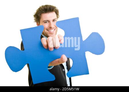 Junger Mann im Anzug mit einem Puzzleteil in der Hand Stockfoto