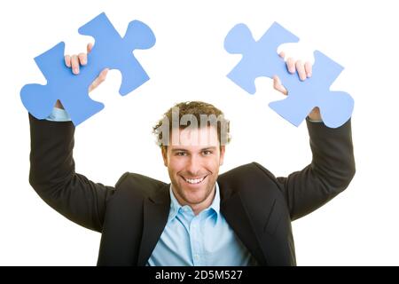 Junger Mann im Anzug mit zwei Puzzleteilen in der Hand Stockfoto